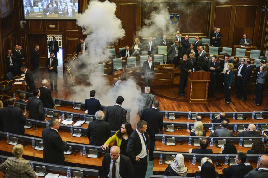 Parliamentarians disperse as a white cloud of tear gas rises in Kosovo's parliament