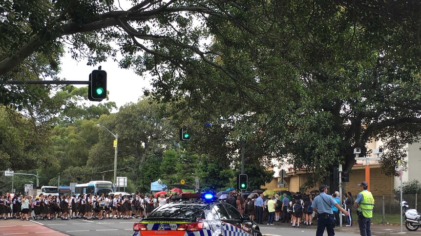 Students cross Cleveland Street in Sydney's east outside Sydney Girls' High School while being escorted by police.
