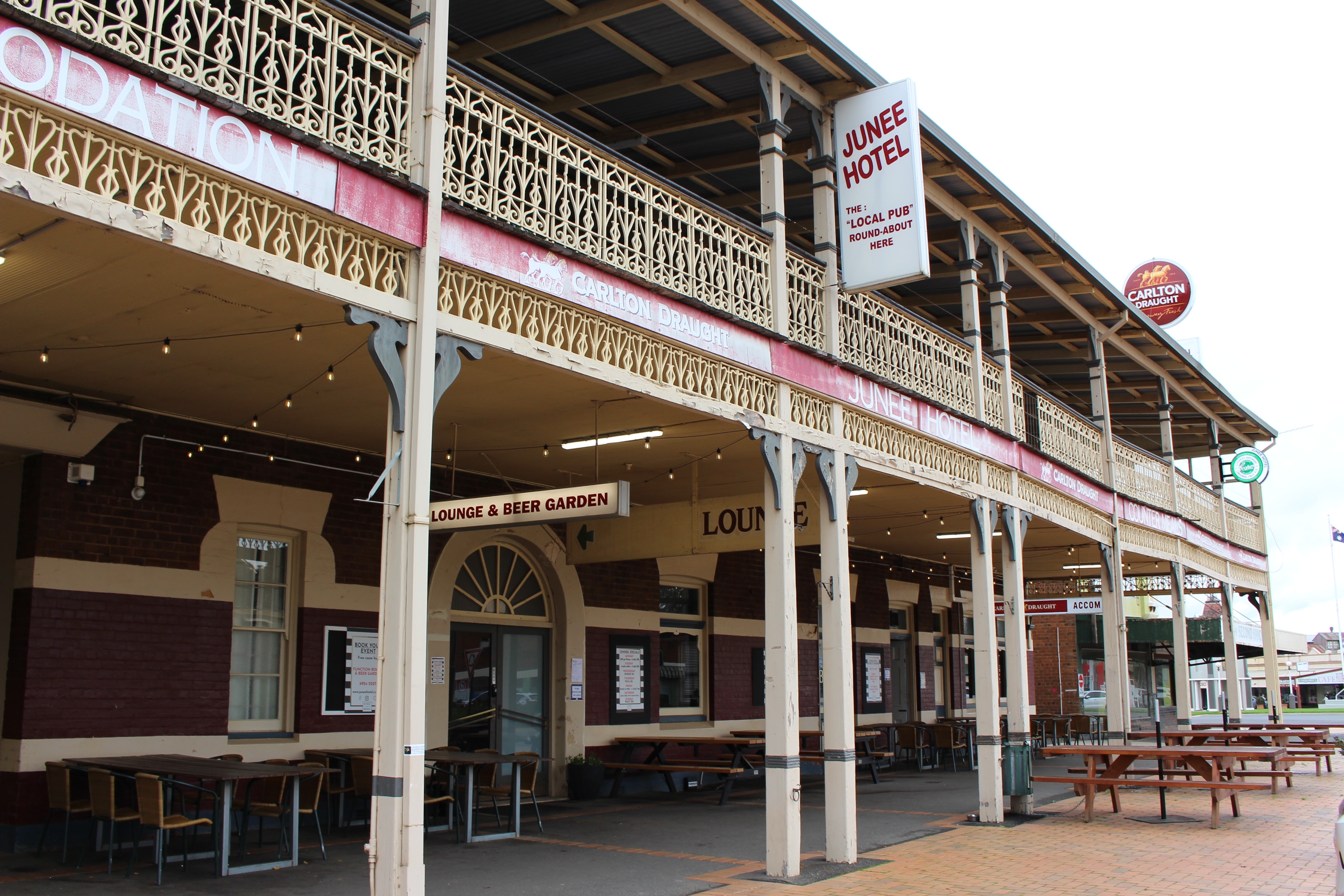 An old red brick pub with cream wrought iron lacework on the veranda