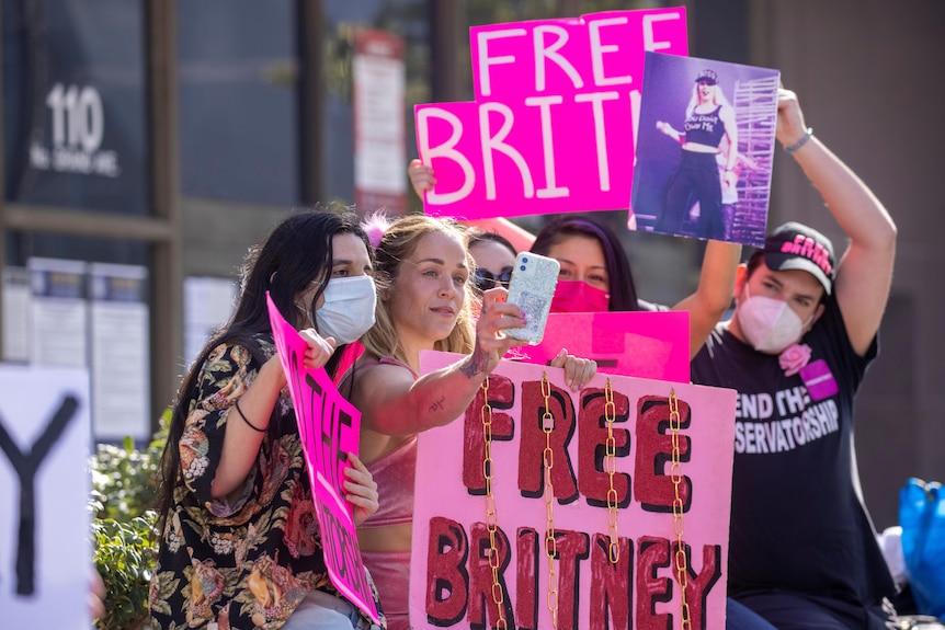 A group of people holding 'Free Britney' posters pose for a photograph