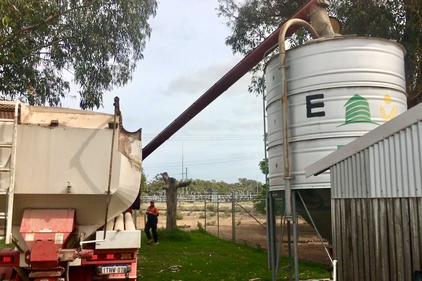 A truck unloads feed into a silo