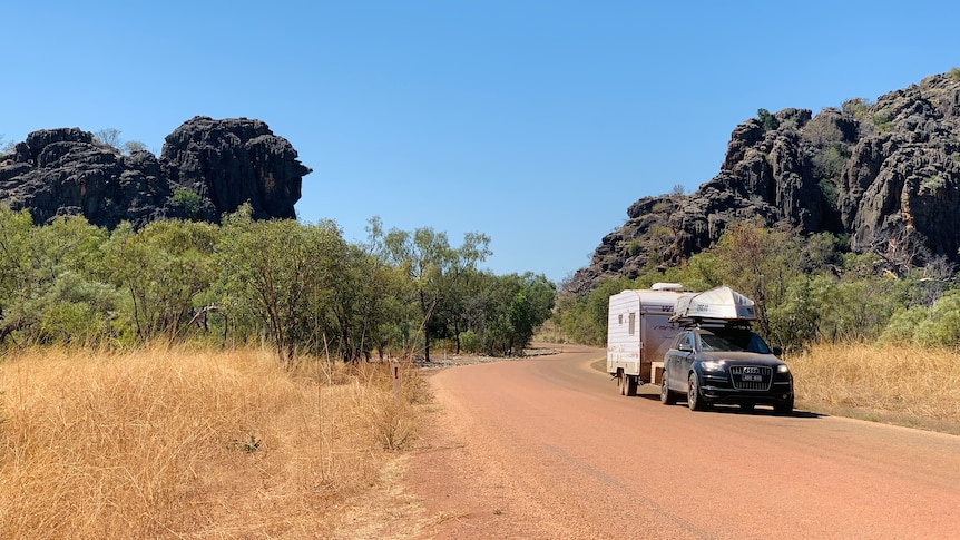 A car tows a caravan along a dirt road