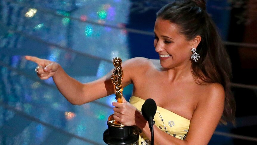 Alicia Vikander points to someone in the audience after receiving the Oscar for Best Supporting Actress.