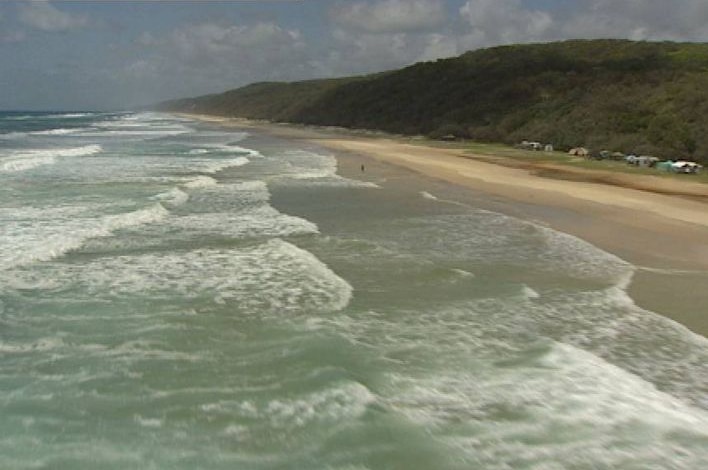 Coastline of Fraser Island showing ocean, beach,  campsites, and heavily forested sand dunes beyond.