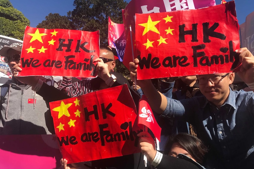 Several students hold up bright red signs