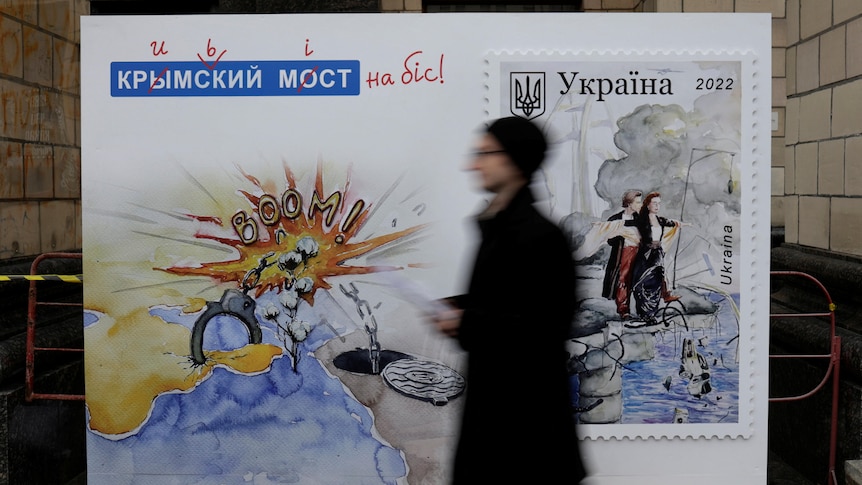 A man walks past a board advertising the new commemorative Crimea bridge destruction Anti-Russian stamps