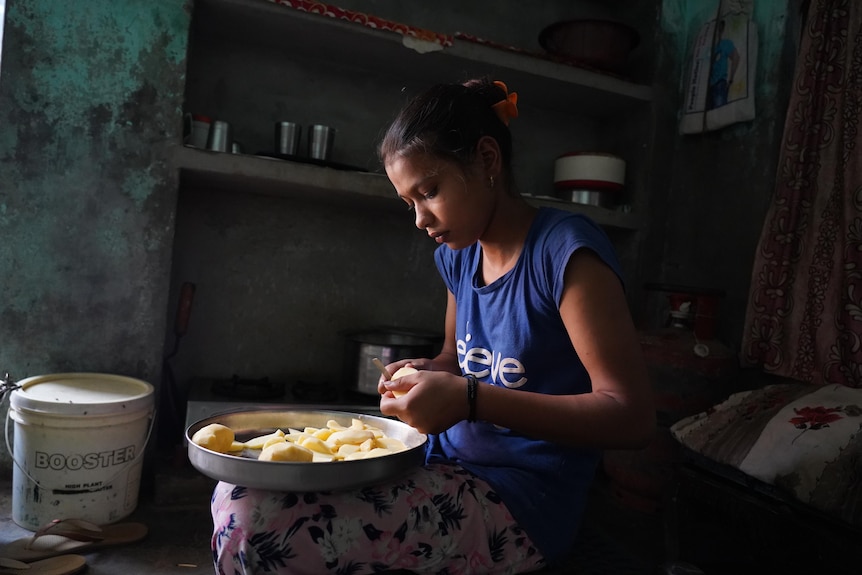 A small Indian girl peeling potatoes 