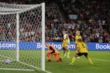 An England women's soccer player sees her backheeled shot go into the net as Swedish keeper and defenders look on.