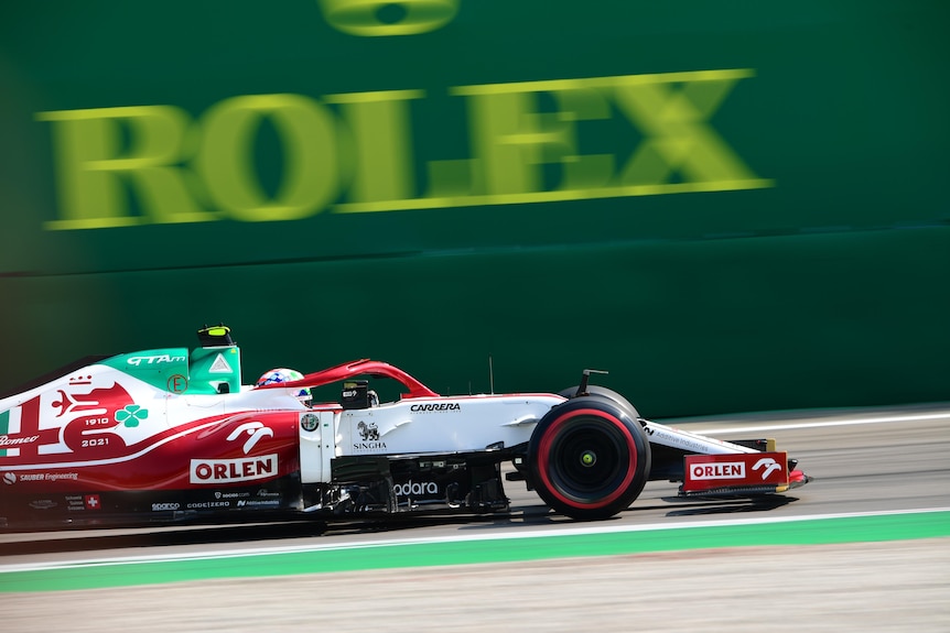 A Formula One car drives past a Rolex sign during practice.