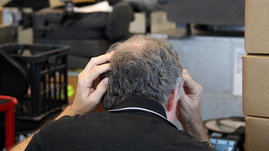 A small business owner, looking at his laptop, looking concerned