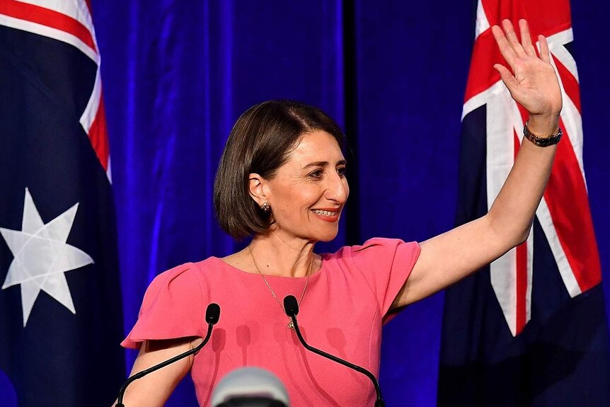 A female politician waving in front of Australian flags.