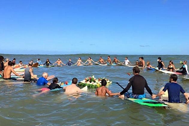 Surfers sit on their boards off the coast of Mexico and link hands during a paddle-out ceremony.