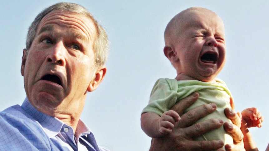 US President George W Bush hands back a crying baby who was handed to him from the crowd.