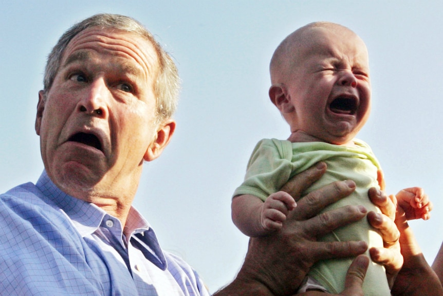 US President George W Bush hands back a crying baby who was handed to him from the crowd.