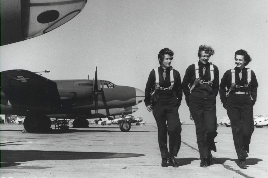 Three women air force pilots walking past twin-engined bombers in 1944.