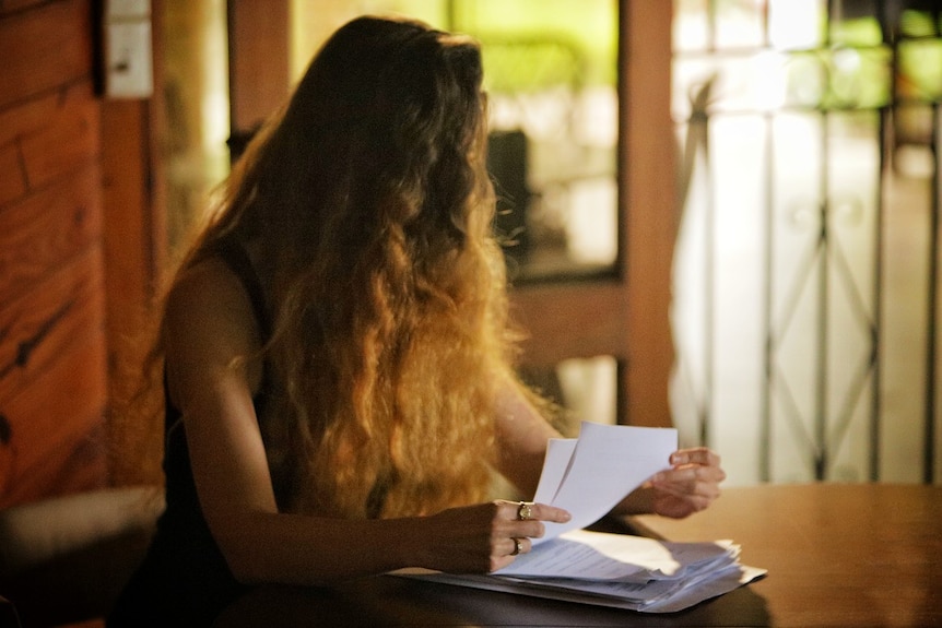 Unidentified woman looks away while holding medical records.