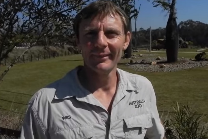 Wes Mannion wears an Australia Zoo uniform and stands near a field