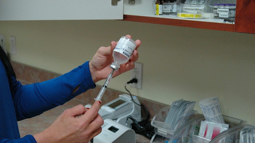 a female hand pulls up on a syringe