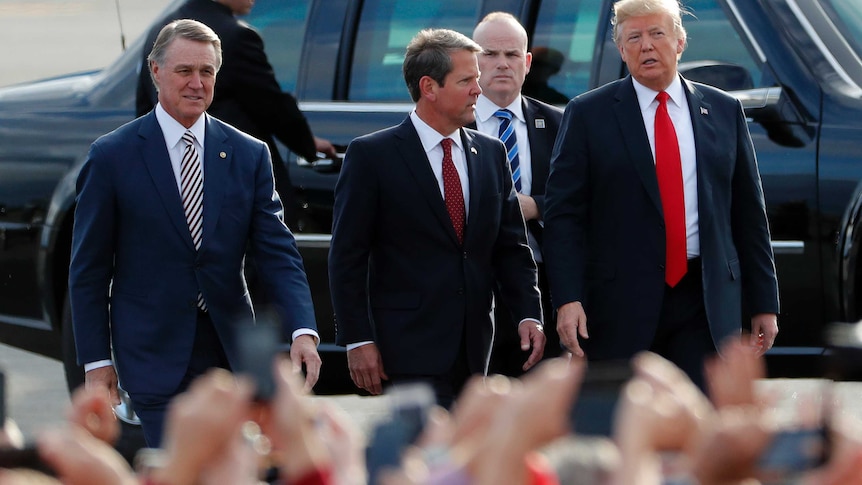 Brian Kemp, centre, walking next to Donald Trump, right, and David Perdue, far left.