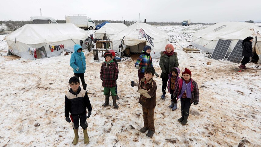 Internally displaced children stand on snow near tents at a makeshift camp in Azaz, Syria.