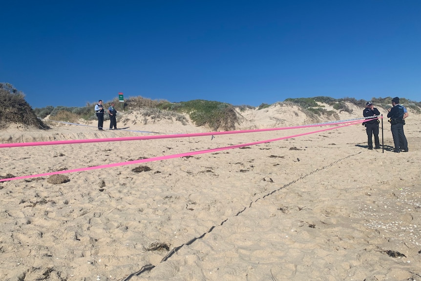 A section of beach cordoned off with police standing at the scene