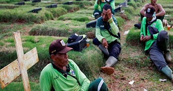 A group of men sit in a cemetery amongst the graves.