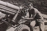 A black and white photo of a man sitting on a gun artillery.