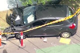Emergency tape surrounding a pole that a black car has crashed into