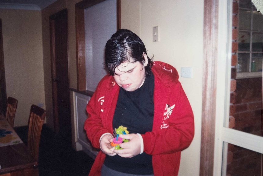 A teenage Yoey stands in a living room.