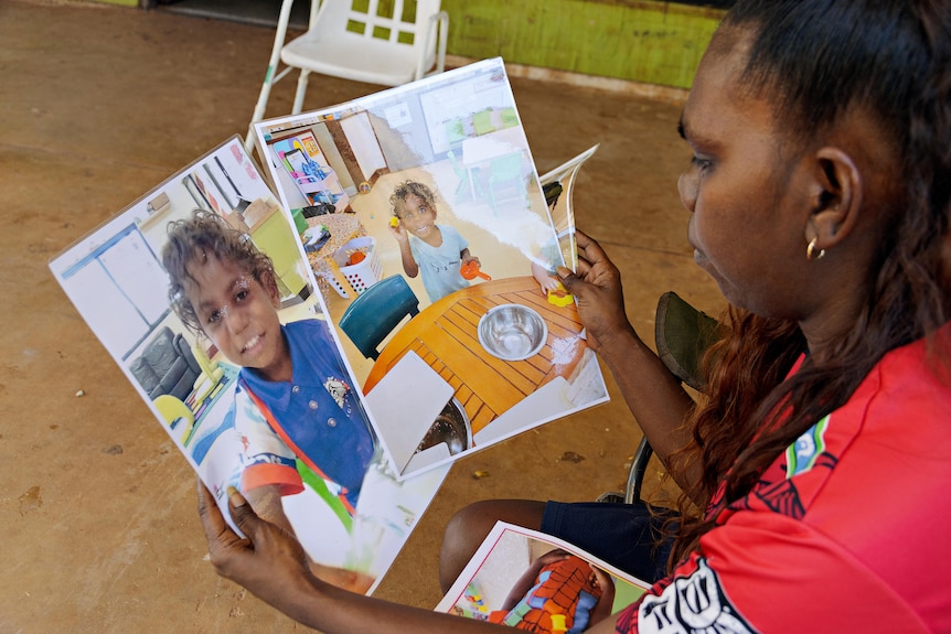 A young woman holds printed out photos of a little boy