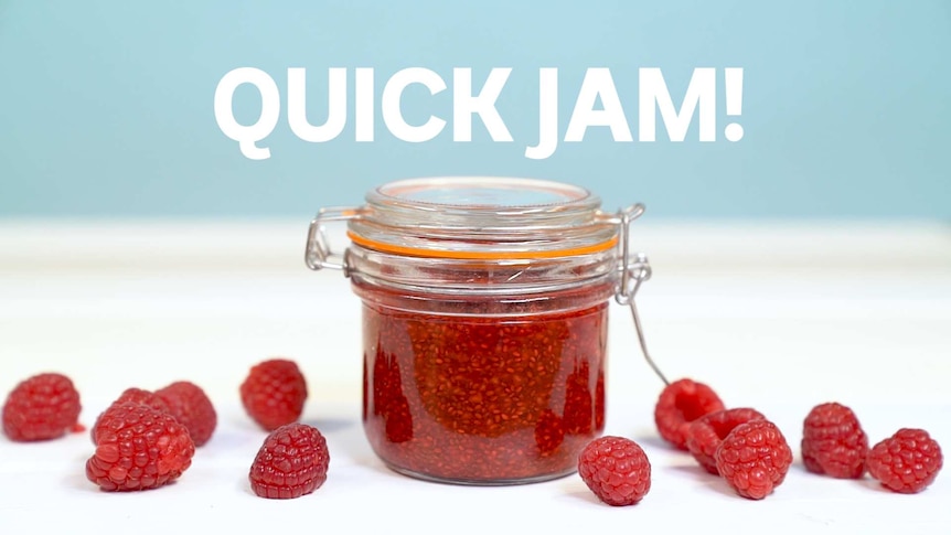 Close up of small jar filled with raspberry chia jam surrounded by fresh raspberries, accompanying our quick recipe