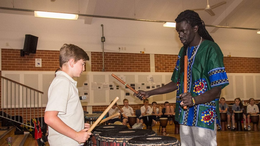 A schoolboy plays West African drums facing Senegalese drummer, Yacou Mbaye