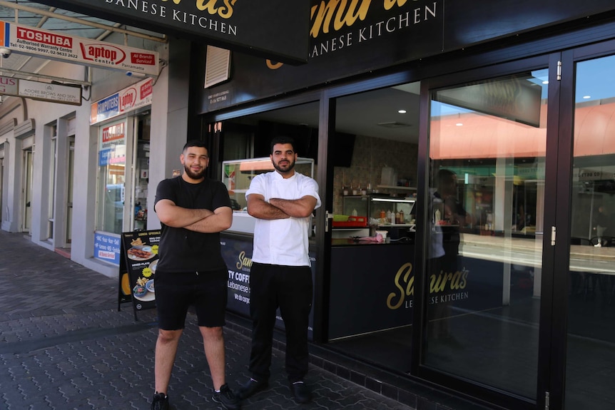 Two men stand outside a cafe