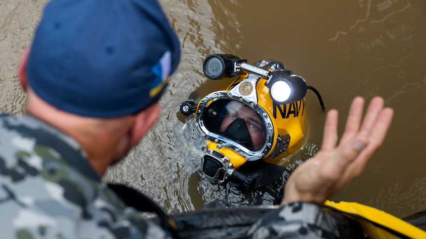 Navy sailor Able Seaman Clearance Diver Jake Phillips prepares to survey ferry terminal pylons along the Brisbane River.