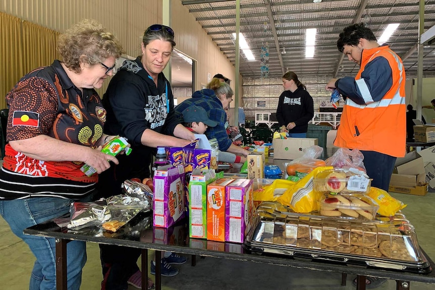 People sorting piles of food on a table in a warehouse