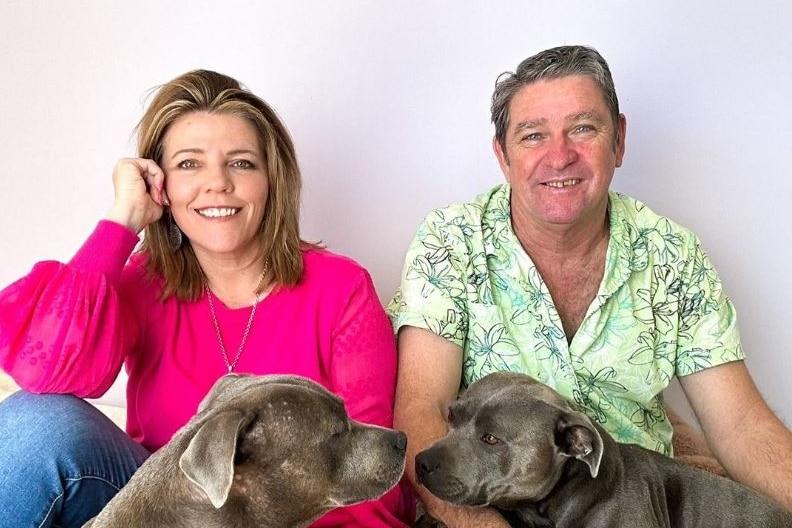 Couple smile at camera with dogs 