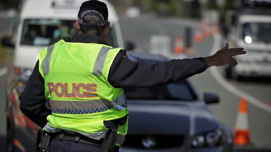 Police directs traffic at a Queensland border checkpoint.