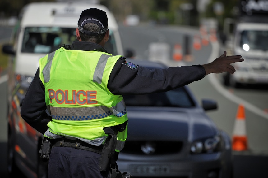 Police directs traffic at a Queensland border checkpoint.