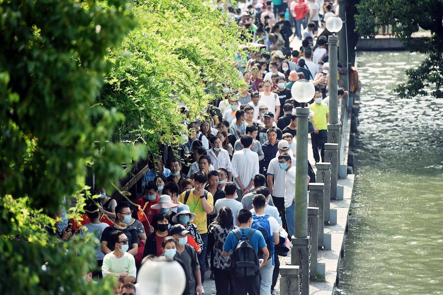 Tourists crowd along a waterfront path