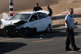 Israeli security forces stand around a crashed car.