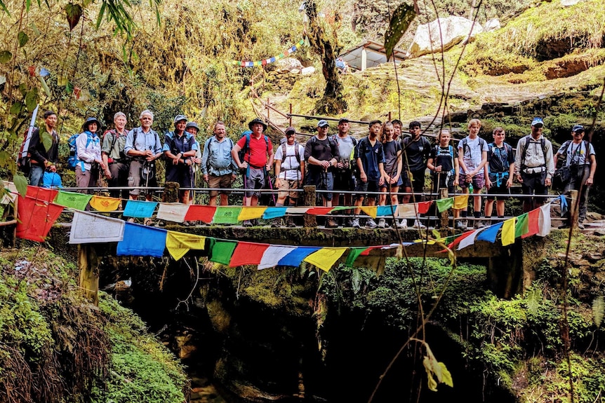 A group of people stand on a bridge behind a lot of flags.