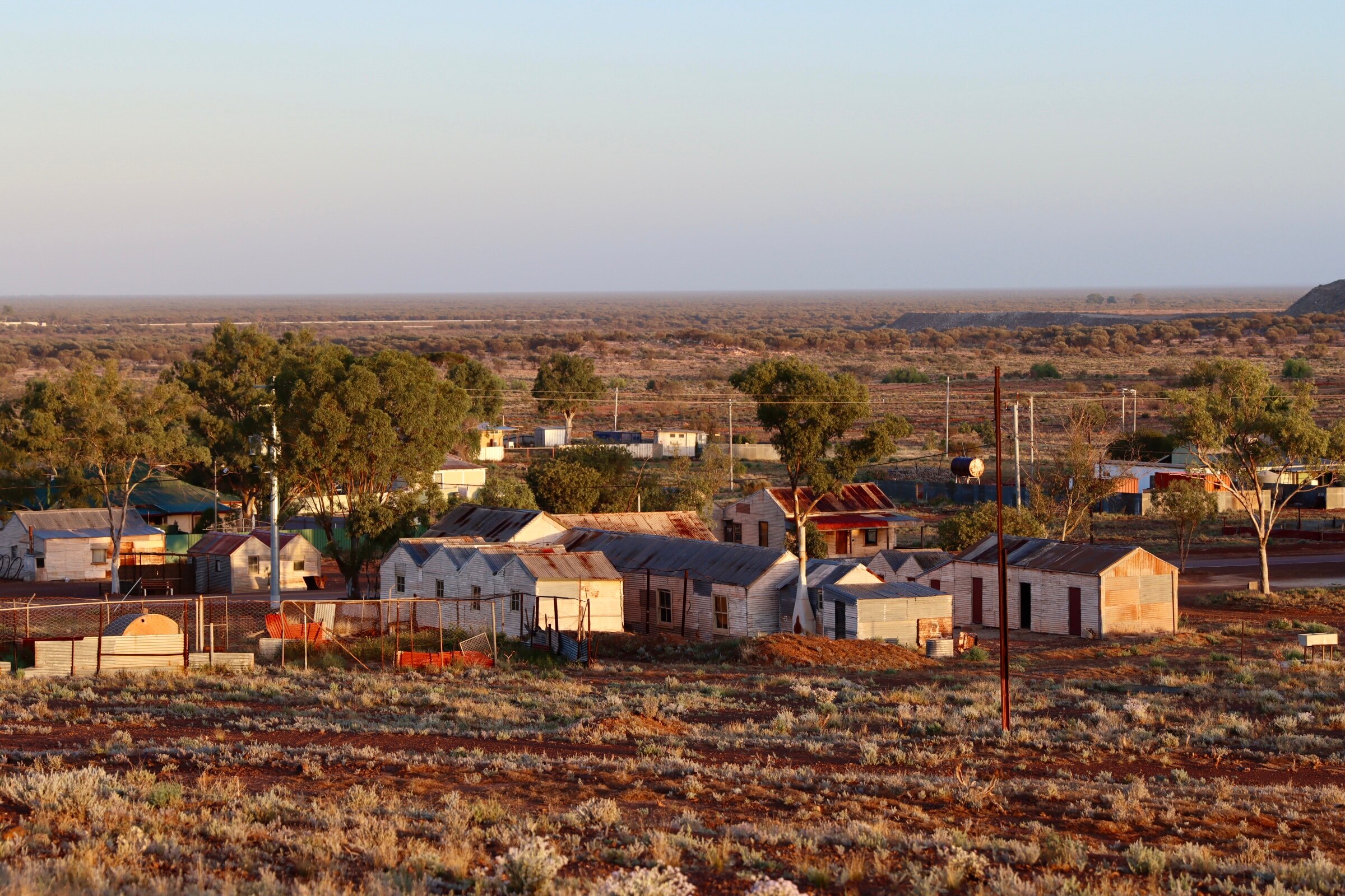 A small town surrounded by a beautiful landscape of red dirt and vegetation.