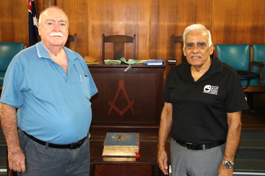 Two elderly gentleman standing in front of a bible 