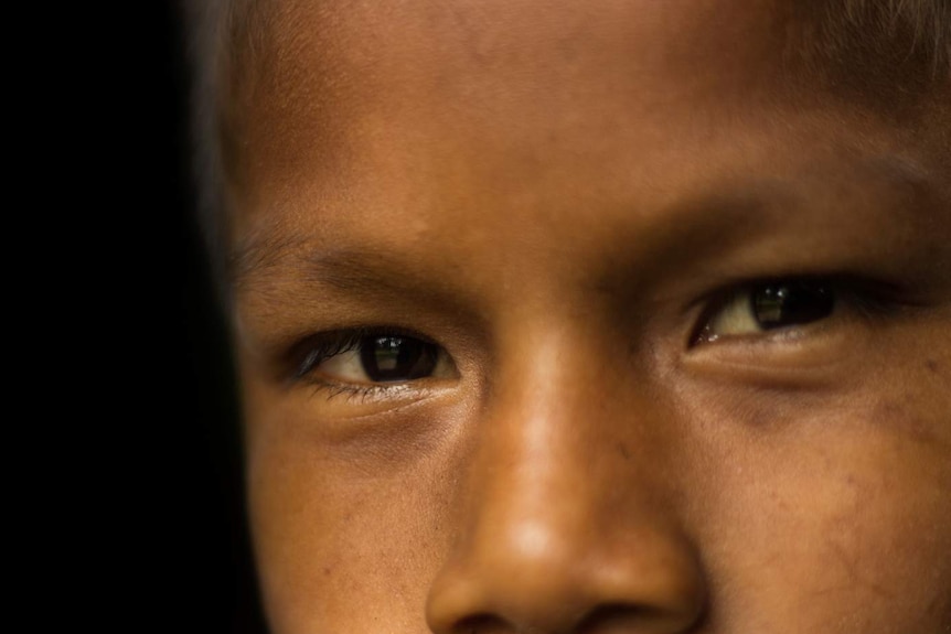 A close up photo of a Murui child's face, showing only his eyes and nose.