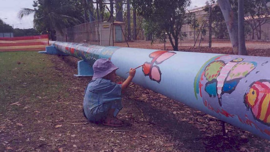 A little kid painting a water pipe