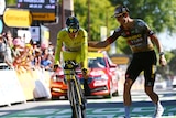 Cyclist Jonas Vingegaard smiles as he crosses the line in the Tour de France time trial, as a teammate pats him on the back.