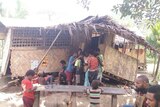 People gather around a home damaged by the earthquake in a village. 
