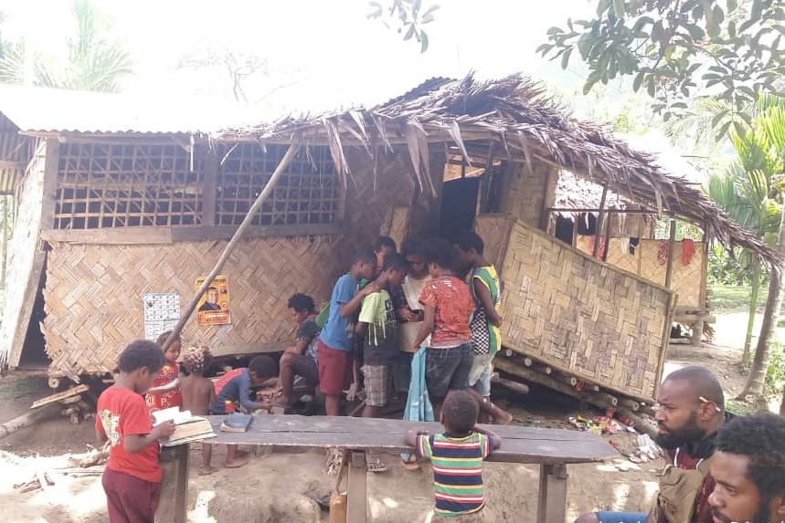 People gather around a home damaged by the earthquake in a village. 