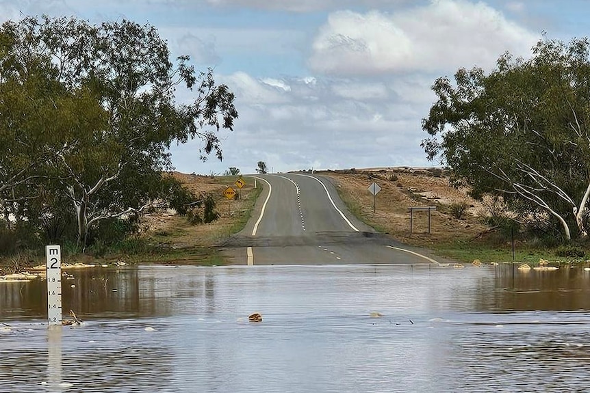 A large body of water covering a road with a flood indicator showing the level is above one metre