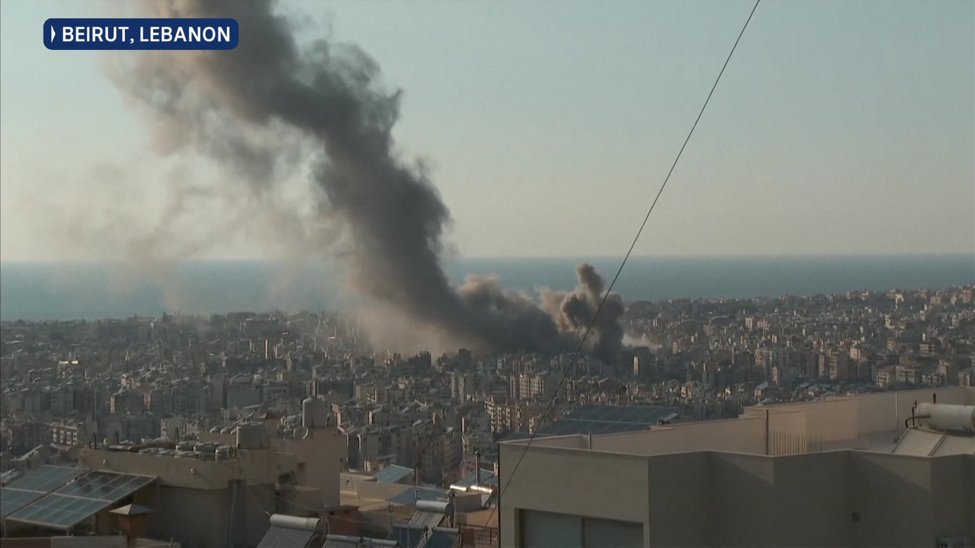A large plume of black smoke rises from a neighbourhood near a coast